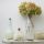 a rustic shelf attached to the wall with a vase of dried flowers and other jars